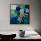 Blue Textured Circles Canvas Art – square blue and teal geometric abstract print in a gold floating frame in a dining room