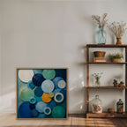 Blue Textured Circles Canvas Art – square blue and teal geometric abstract print in an oak floating frame styled on a shelf