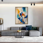 Cobalt and Saffron Swirl Canvas Art – vertical cobalt and orange abstract print in a gold floating frame in a living room with charcoal accents