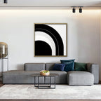 Monochrome Arc Canvas Art – square black and white geometric abstract print in a gold floating frame in a living room with charcoal accents
